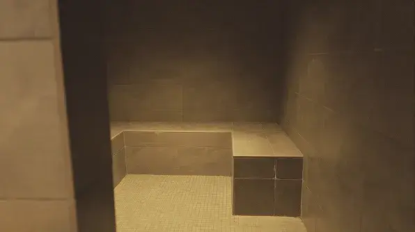 A modern, tiled steam room featuring built-in seating and soft lighting for relaxation.