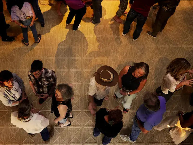 Aerial view of a lively gathering with diverse groups of people engaged in conversation on a patterned floor.