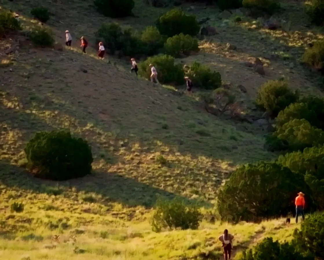 Hikers ascend a grassy hillside, enjoying nature and the outdoors in a scenic landscape.