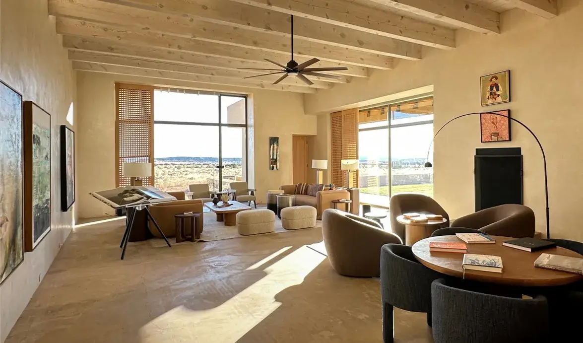 Modern living room with large windows, minimalist furniture, and natural light highlighting a cozy, inviting atmosphere.