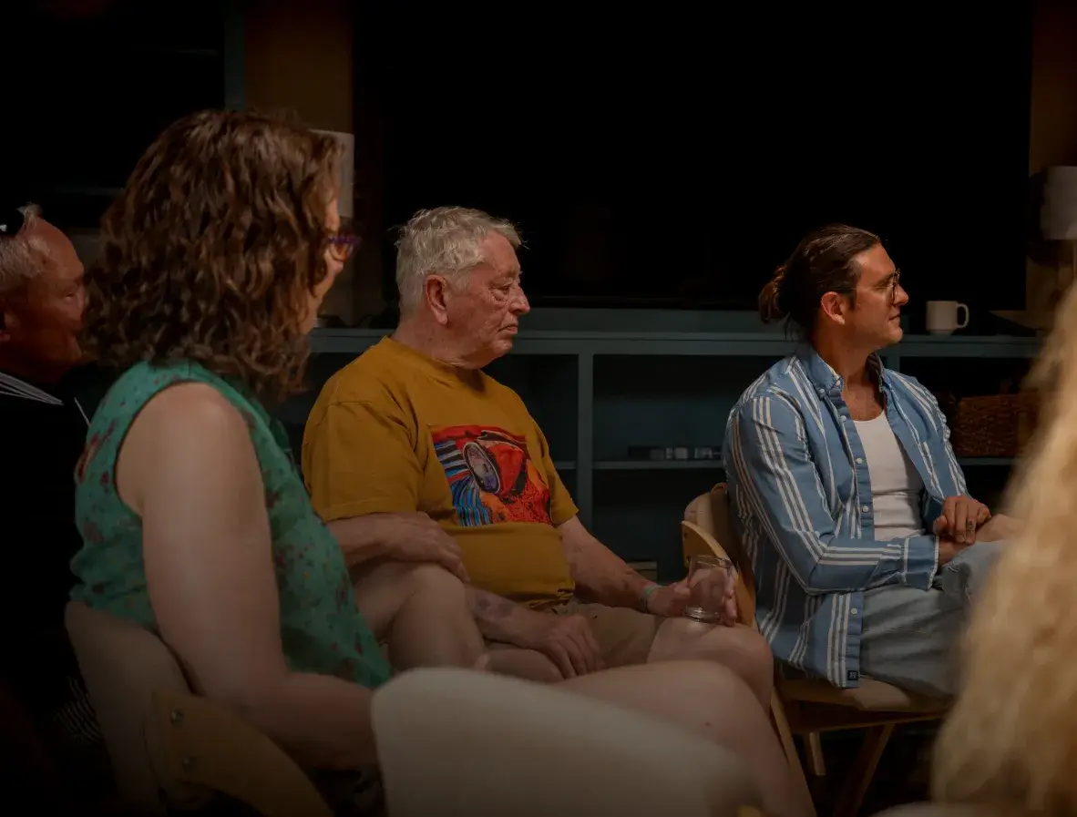 A diverse group of people engaged in a discussion, seated in a cozy, well-lit room.