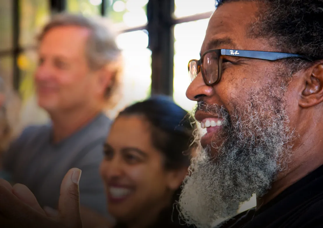 A diverse group of people smiles and engages in conversation, highlighting a warm and joyful social atmosphere.